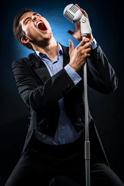 Homem de casaco preto elegante e camisa azul cantando — Fotografia de Stock