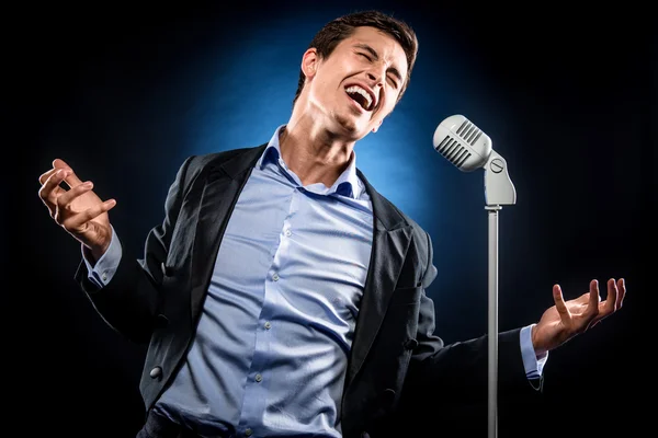 Hombre de elegante chaqueta negra y camisa azul cantando —  Fotos de Stock