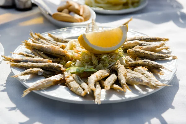Plate of deep fried anchovies with lemon and salad — Stock Photo, Image
