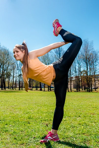 Mladá atraktivní žena dělá protahovací cvičení venku — Stock fotografie