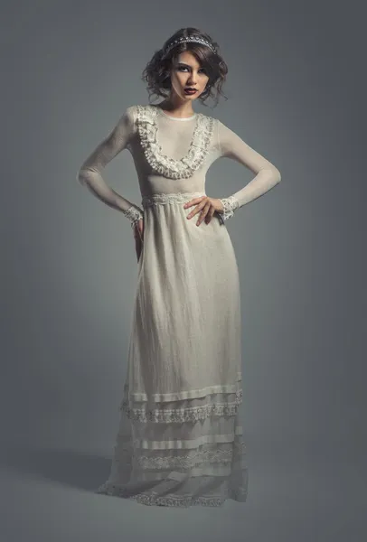Κομψό νεαρή γυναίκα στο λευκό μακρύ φόρεμα που θέτουν σε εσωτερικούς χώρους — Φωτογραφία Αρχείου