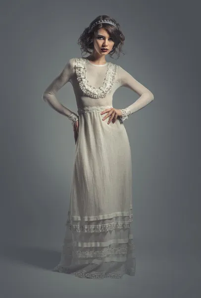 Elegant young woman in white long dress posing indoors — Stock Photo, Image