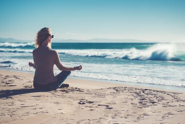 Genç bir kadın sahilde meditasyon yapıyor. — Stok fotoğraf