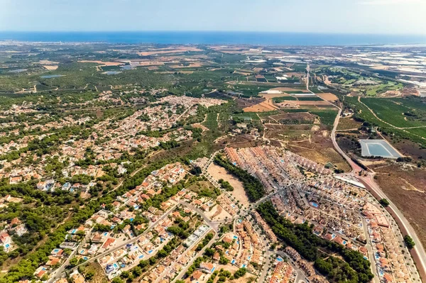 Pinar de Campoverde 'nin kırsal manzarası, tarım arazileri, tarım arazileri, güneşli bir günde yerleşim bölgesi modern evleri. Costa Blanca, Alicante ili, İspanya 'nın güneyi.