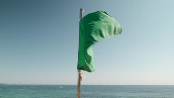 在阳光明媚的夏日 在蓝天和地中海背景的映衬下 高举绿旗 颁发给符合欧盟清洁标准的浴场的标志 科斯塔布兰卡西班牙 — 图库视频影像