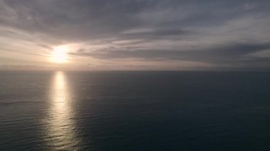 Sakin Akdeniz 'in üzerindeki ufuk ışıl ışıl, güzel güneş doğarken. Parlayan güneş, pürüzsüz deniz manzarası, gri renkli bulutlu arka plan. İnsan yok, sabah manzarası. İspanya, Calpe