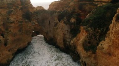 Uçan insansız hava aracı bakış açısı azgın okyanus ve Ponta da Piedade burnu. Kireçtaşı kıyı şeridi boyunca sarı uçurumlar, Lagos kasabası, Portekiz 'in en ünlü turistik merkezi.