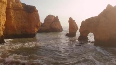 Uçan insansız hava aracı bakış açısı azgın okyanus ve Ponta da Piedade burnu. Kireçtaşı kıyı şeridi boyunca sarı uçurumlar, Lagos kasabası, Portekiz 'in en ünlü turistik merkezi.