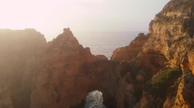 Uçan insansız hava aracı bakış açısı azgın okyanus ve Ponta da Piedade burnu. Kireçtaşı kıyı şeridi boyunca sarı uçurumlar, Lagos kasabası, Portekiz 'in en ünlü turistik merkezi.