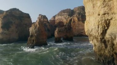Uçan insansız hava aracı bakış açısı azgın okyanus ve Ponta da Piedade burnu. Kireçtaşı kıyı şeridi boyunca sarı uçurumlar, Lagos kasabası, Portekiz 'in en ünlü turistik merkezi.