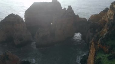 Uçan insansız hava aracı bakış açısı azgın okyanus ve Ponta da Piedade burnu. Kireçtaşı kıyı şeridi boyunca sarı uçurumlar, Lagos kasabası, Portekiz 'in en ünlü turistik merkezi.
