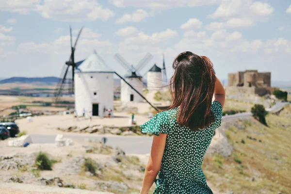 リアバックビュー若い女性はConsuegraの町で有名な古い風車の背景に対してポーズ カスティーリャ マンチャ州 スペインのトレド 観光スポットや旅行先のコンセプト — ストック写真