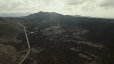 Timanfaya Ulusal Parkı 'nın volkanik manzarası, bulutlu arka planda dağlık arazi. Kanarya Adaları, Lanzarote, İspanya. Seyahat yeri, turizm, ünlü yerler konsepti.