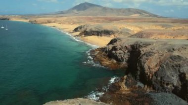 Drone point of view, aerial shot of sandy beach of Lanzarote. People relax on most popular Papagayo beach of Lanzarote, cove of white sand, Atlantic Ocean bay, crystal clear, green water. Spain