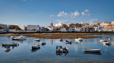 Fishing boats docked in Atlantic Ocean bay and view to the Arrecife town. Charco de san Gines. Lanzarote Island. Canaries, Spain. Travel destinations, scenic landmarks concept