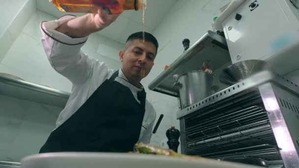 围裙男厨师把瓶子倒醋或油放在准备好的菜里 准备上菜 食肆烹调概念 — 图库视频影像