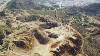 Aerial shot, drone point of view from above old abandoned mines of Mazarron in Murcia on blue sky background during sunny summer day. Mineral extraction industry, history concept. Spain 