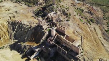 Aerial shot, drone point of view old abandoned buildings of mines of Mazarrn in Murcia on blue sky background during sunny summer day. Mineral extraction industry, history concept. Spain 