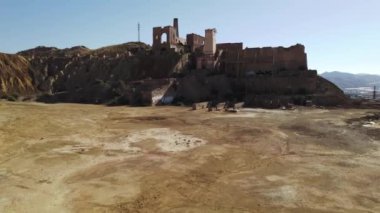 Aerial shot, drone point of view old abandoned buildings of mines of Mazarrn in Murcia on blue sky background during sunny summer day. Mineral extraction industry, history concept. Spain 