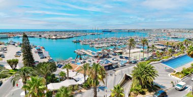 Panoramic photo Torrevieja puerto seaport view from above, scenic palm-tree lined seafront, nautical vessels moored on Mediterranean Sea bay. Costa Blanca. Province of Alicante. Spain. Travel concept clipart