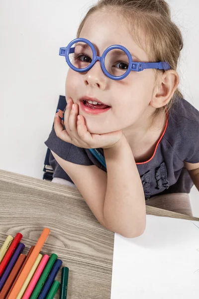 Sevimli küçük kız mavi gözlük okul masasında boyama — Stok fotoğraf