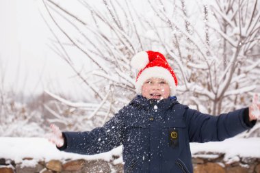 Noel Baba şapkalı mutlu çocuk kışın bahçede
