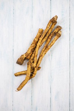 Beyaz arka planda ahşap üzerine baharatlı yabanturpu kökü, üst görünüm