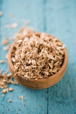 Kesilmiş meyan kökü kökü. Tahta bir kasede balgam etkisi yaratıyor.