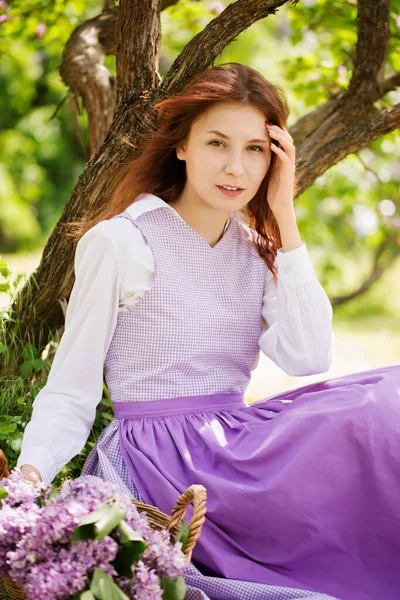 若い美しい赤髪の女性がライラックを咲かせる庭のヴィンテージドレス — ストック写真