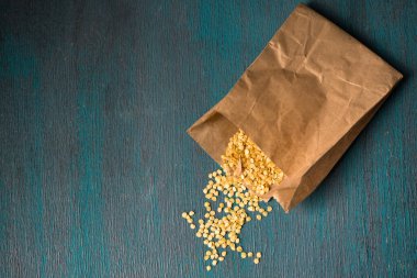 Ahşap zemin üzerinde kuru biber tohumları olan kağıt torba.