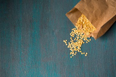 Ahşap zemin üzerinde kuru biber tohumları olan kağıt torba.