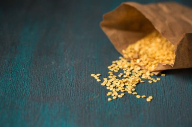 Ahşap zemin üzerinde kuru biber tohumları olan kağıt torba.