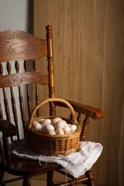 Antika bir sandalyede kırsal tarzda büyük bir tavuk yumurtası sepeti.