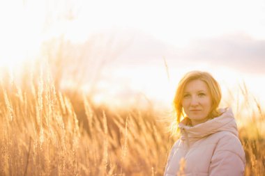 Young blonde woman on a lonely walk in the rays of the setting sun