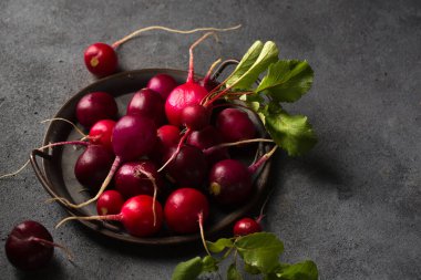 Koyu arkaplanda eski bir tepside yuvarlak renkli turp.