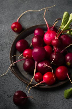 Koyu arkaplanda eski bir tepside yuvarlak renkli turp.