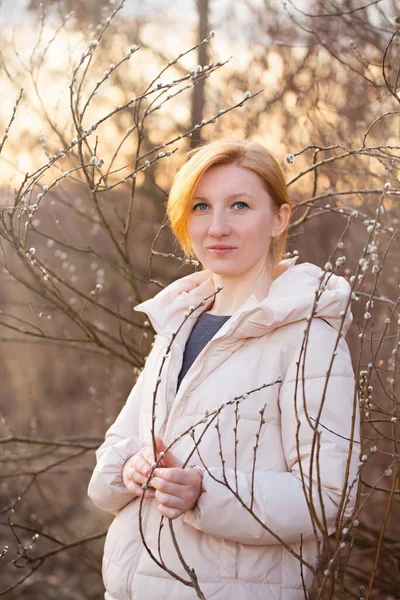 Sarışın genç kadın güneşte söğüdün yanında