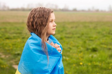Ukrayna bayrağına sahip küçük bir kız ülkesinin zaferi için dua ediyor.