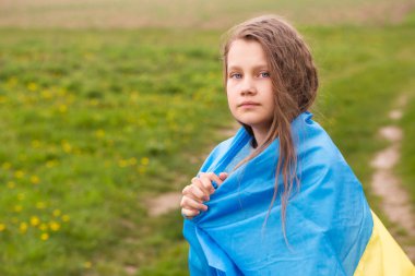 Ukrayna bayrağına sahip küçük bir kız ülkesinin zaferi için dua ediyor.