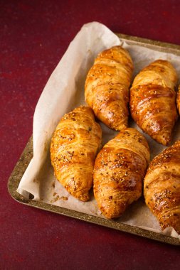 Burgundy arka planında fırında pişmiş kruvasan.