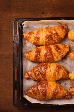 Büyük kruvasanlar ahşap bir zemin üzerinde metal kabartma çarşafları, üst görünüm