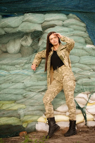 Ukrainian woman in the uniform of the armed forces of Ukraine on the background of sandbags