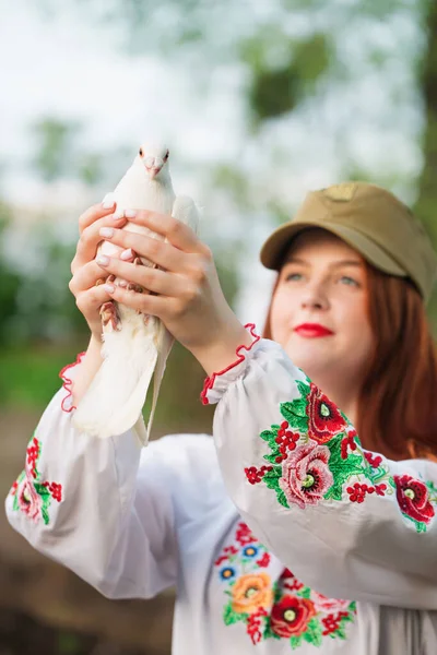 A beautiful Ukrainian woman in Ukrainian national embroidered dress with a white dove in her hands, a symbol of peace in Ukraine