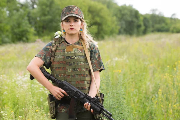 Ukrainian female military servicewoman with a machine gun in her hands in the middle of a field