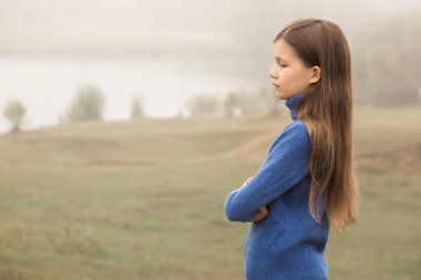 A beautiful young girl was alone in nature in a foggy morning