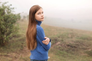 A beautiful young girl was alone in nature in a foggy morning