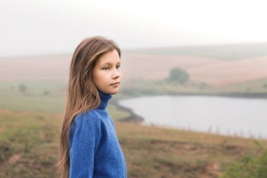 A beautiful young girl was alone in nature in a foggy morning