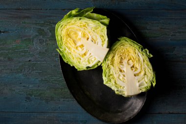 Young early cabbage cut in half on a dark background