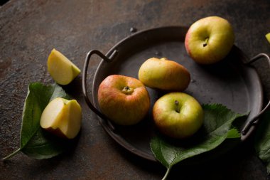 Small flattened apples on a metal tray on a dark background