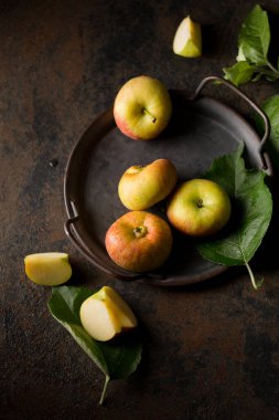 Small flattened apples on a metal tray on a dark background